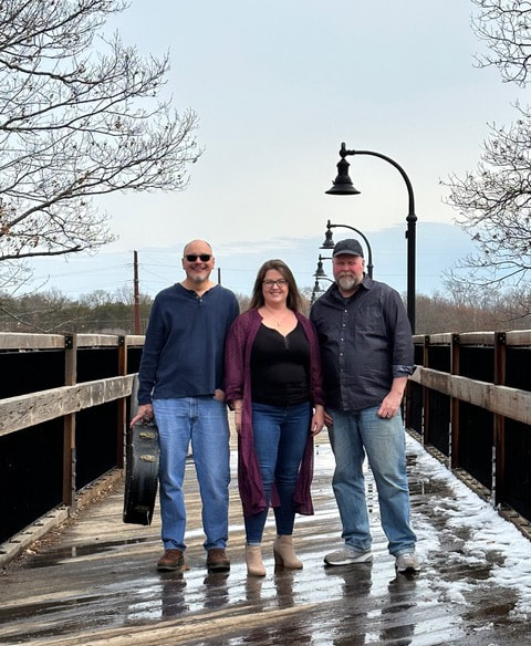 Photo of the three band members of Highbridge posing together on a bridge