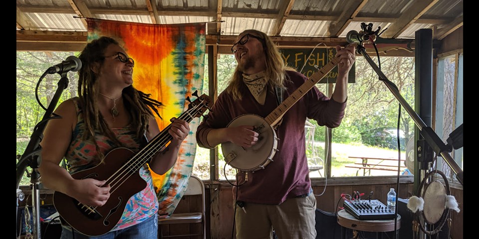 Photo of the two band members of The Rock Creek Song Dogs playing banjo and mandolin together outdoors.